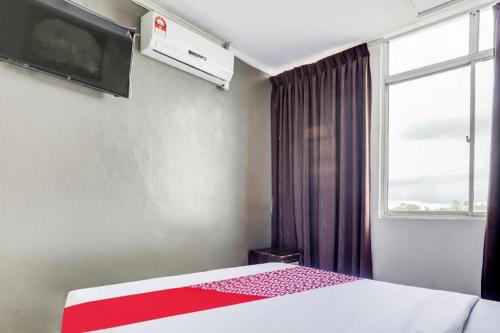 a bedroom with a bed and a window and avertisement at OYO 90376 Centre Point Hotel in Limbang