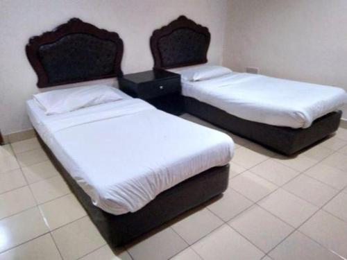 two beds in a hotel room with white sheets at OYO 90376 Centre Point Hotel in Limbang