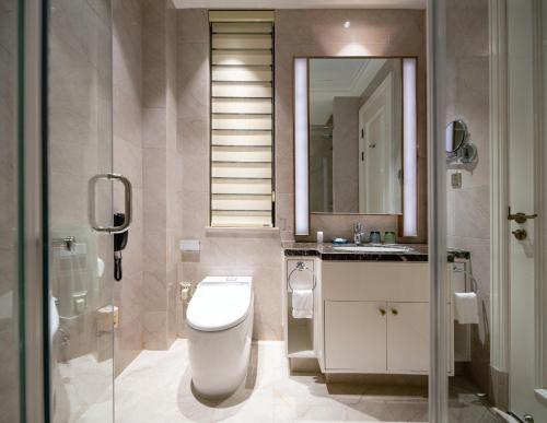 a bathroom with a toilet and a sink and a mirror at Wyndham Grand Xi'an Residence in Xi'an