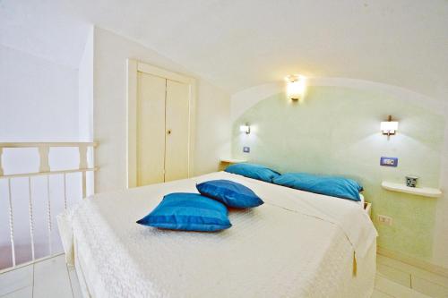 a white bedroom with blue pillows on a bed at Alfieri Rooms - Amalfi coast in Atrani