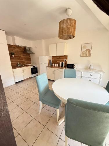 une cuisine avec une table blanche et des chaises bleues dans l'établissement Charme et Confort, plein centre, à Obernai