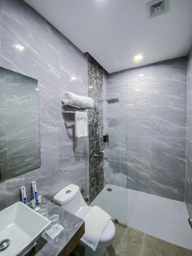 a bathroom with a toilet and a sink and a shower at The South Hideaway Oslob 
