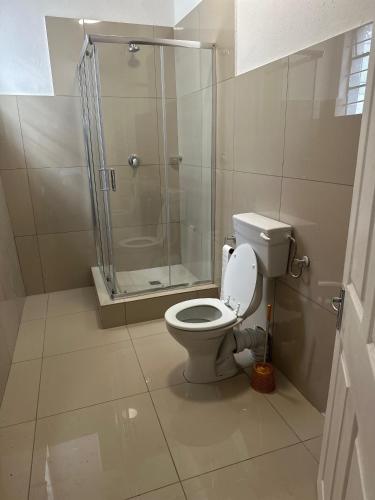 a bathroom with a toilet and a glass shower at Biscuit Mill Woodstock Backpackers in Cape Town