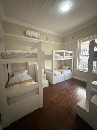 a room with three bunk beds and a window at Biscuit Mill Woodstock Backpackers in Cape Town