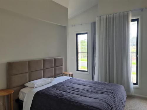 a bedroom with a large bed and two windows at Songlark Street, 54 in Bermagui