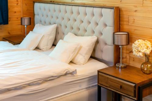 a bed with white sheets and pillows next to a table at reBORONA in Őriszentpéter