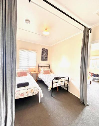 a bedroom with two beds and a window at Denham Cottage - Quart Pot Creek in Stanthorpe
