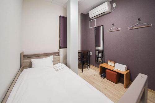 a bedroom with a white bed and a desk and a bed sidx sidx at 4S STAY Awaikeda ikedaonsenyoko in Miyoshi
