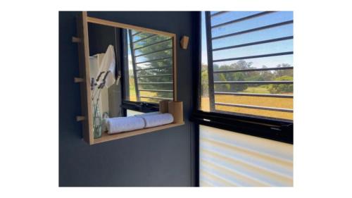 a mirror on a wall next to a window at The Ridge by Tiny Away in Korweinguboora