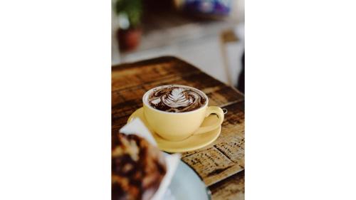 a cup of coffee on a table with a plate of food at The Ridge by Tiny Away in Korweinguboora