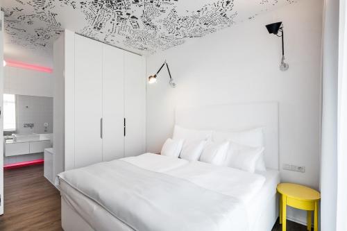 a white bedroom with a white bed and a yellow stool at Pytloun Grand Hotel Imperial in Liberec
