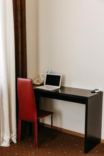 a desk with a laptop and a red chair at Summit Villa in Chişinău