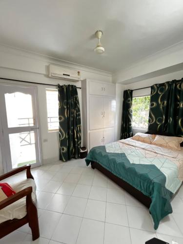 a bedroom with a bed with green sheets and windows at Serenity by Limitless Stays in Puttaparthi
