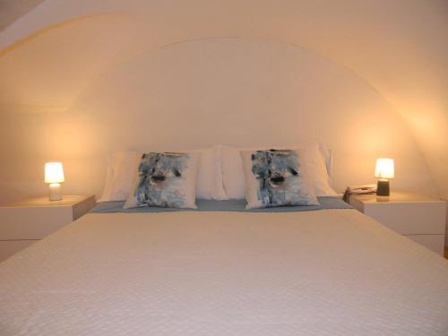 a white bed with two pillows and two lamps at Dammuso Rossini in Ragusa