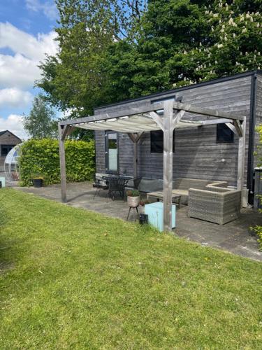 a wooden pavilion with a picnic table and a bench at Tiny House Indy-Blue in Giethoorn