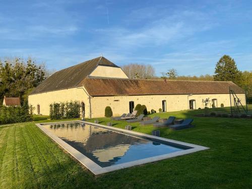un bâtiment avec une piscine en face d'une maison dans l'établissement 5-star castle, à Yermenonville