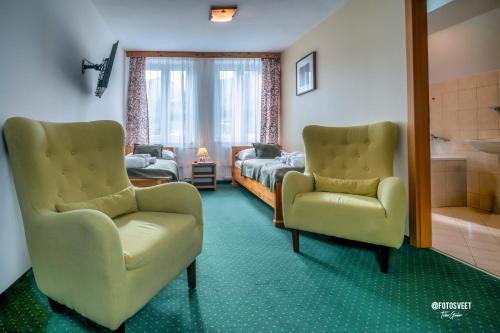 a room with two chairs and a bed and a mirror at Wellness Penzion Zora Family in Tatranská Lomnica