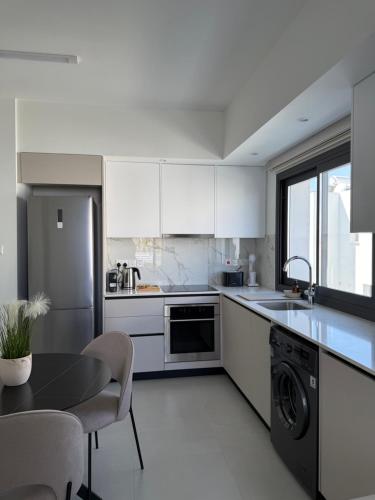 a kitchen with white cabinets and a table and a dishwasher at ΘΕΑ 5 Comfortable 1BR and 2BR Apartments in Mor Menekshe