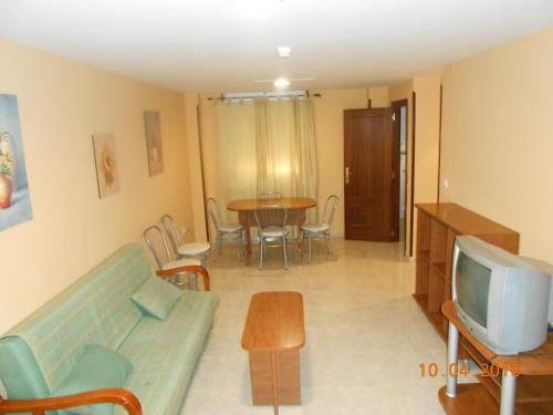 a living room with a couch and a tv and a table at Apartahotel Los Hermanos in Ocaña