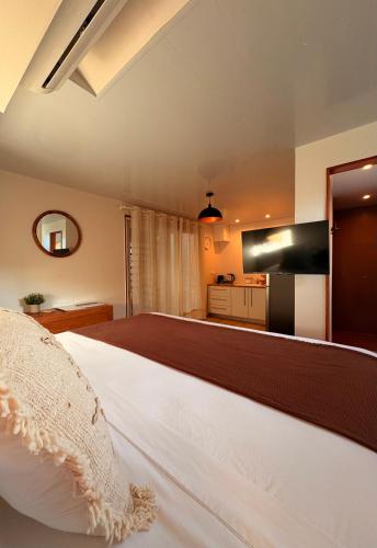 a bedroom with a white bed and a kitchen at Chez PASCAL et KIM in Papetoai