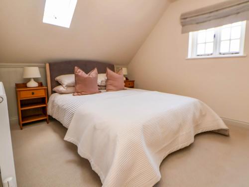 a bedroom with a large white bed with pink pillows at Egerton Cottage in Crewe