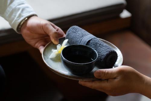 a person holding a plate with a bowl of food at Le Sen Boutique Hotel in Luang Prabang