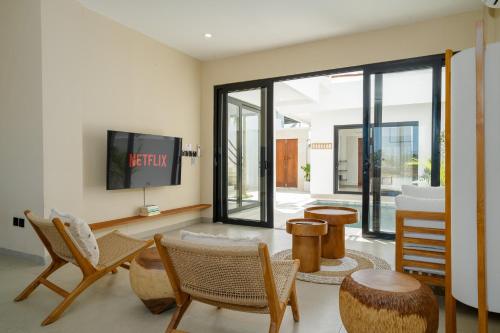 a living room with a tv and some chairs at Villa Le Blanc in Tumbak Bayuh