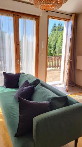 un canapé vert assis dans une pièce avec des fenêtres dans l'établissement Appartement plein centre avec terrasse, à Font-Romeu