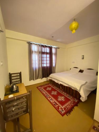 a bedroom with a bed and a table and a window at SomaHouse and Cafe, Spiti in Kaza