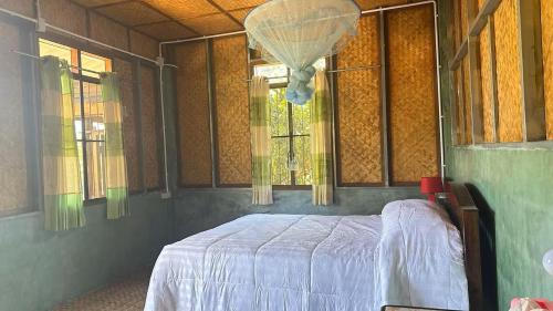 Un dormitorio con una cama en una habitación con ventanas. en Far Far Away Homestay Chiangdao, en Ban Tham