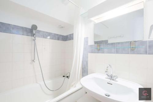 une salle de bain blanche avec une douche et un lavabo dans l'établissement Biscarrosse Plage: Duplex pour 4 personnes, à Biscarrosse