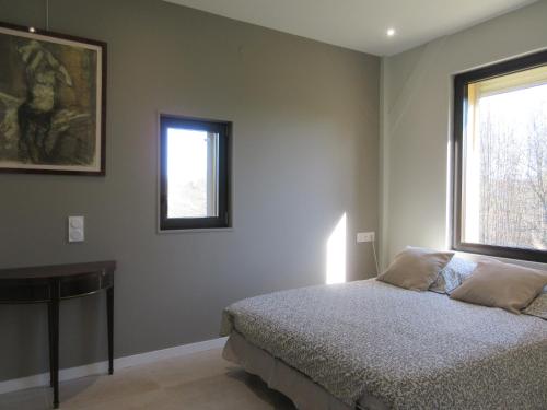 Domaine de l homme في Saint-Vincent-le-Paluel: غرفة نوم بسرير وطاولة ونوافذ