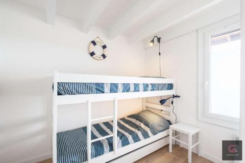 Ce lit superposé blanc se trouve dans un dortoir doté d'une fenêtre. dans l'établissement Biscarrosse Plage: Duplex pour 4 personnes, à Biscarrosse