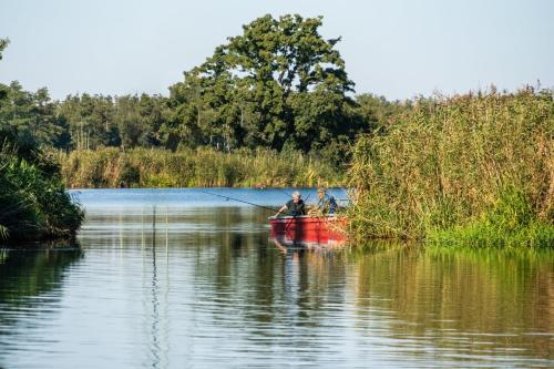 two people in a red boat on a lake at Ferienwohnung Sophienhof in Loitz