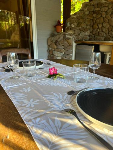 a table with wine glasses and a pink flower on it at Chez PASCAL et KIM in Papetoai