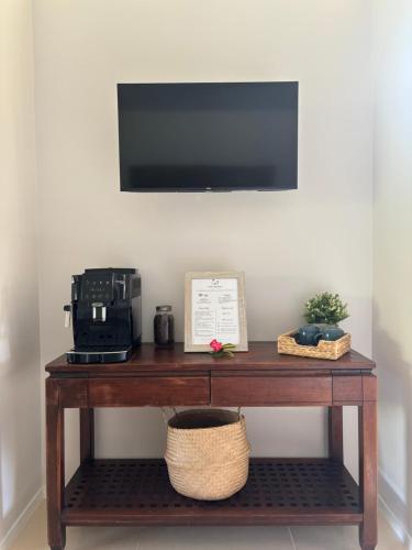 a table with a coffee machine and a television on a wall at Chez PASCAL et KIM in Papetoai