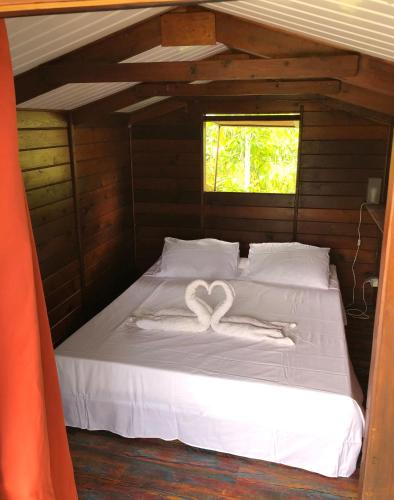 a bed with two heart shaped towels on it at Les pieds dans l’eau à huahine. Maison climatisée in Parea