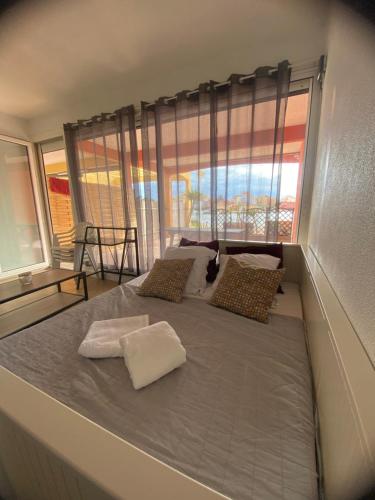 un grand lit dans une chambre avec une grande fenêtre dans l'établissement appartement climatisé au bord du lac marin, au Barcarès