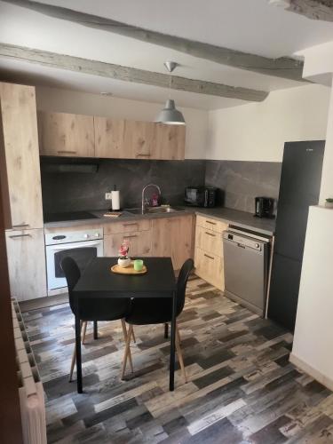 - une cuisine avec une table et une table noire dans l'établissement Charmante maison de village, à Saint-Paul-les-Fonts