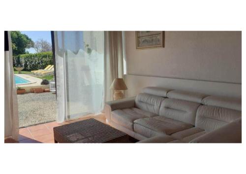 un salon avec un canapé et une porte coulissante en verre dans l'établissement Gite Piscine Périgord, à Saint-Cyprien