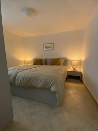 a bedroom with a bed with two lamps on it at Alto Mare Apartments in Selce