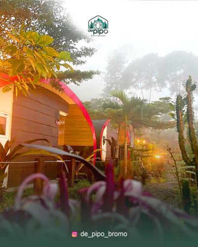 a cabin in a garden with flowers in the foreground at de Pipo Bromo in Sukapura
