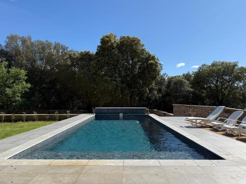 une piscine avec deux chaises longues et une piscine dans l'établissement Valboissière Mas avec piscine, à Brissac