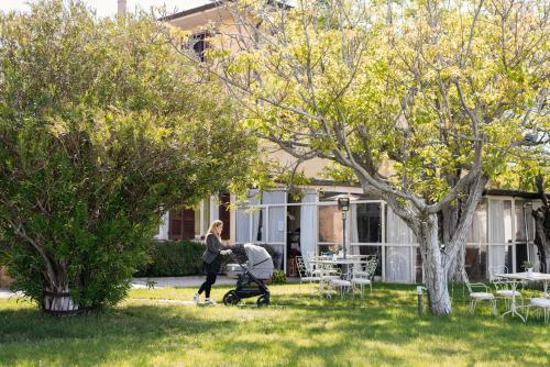 a woman pushing a baby in a stroller in a yard at Agriturismo Podere L'Agave in San Vincenzo