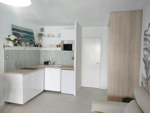 une cuisine blanche avec un évier et un micro-ondes dans l'établissement Bord de mer avec jardin, aux Lecques