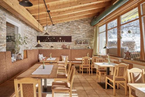 a restaurant with tables and chairs and a brick wall at Bio Hotel Stillebach in Sankt Leonhard im Pitztal