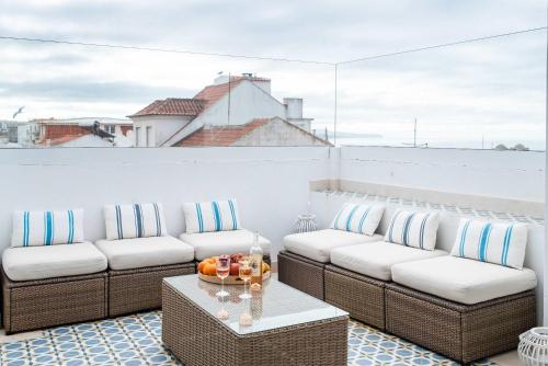 a balcony with couches and a table on a roof at Ocean View Penthouse - Central Ericeira in Ericeira