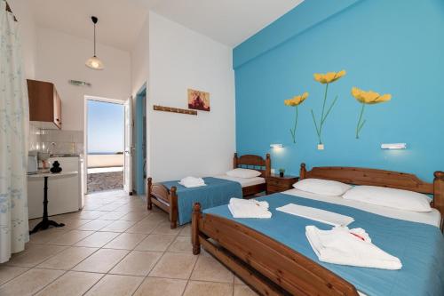 a room with two beds and a kitchen in it at Mikro Nisi Studios & Apartments in Agios Nikolaos