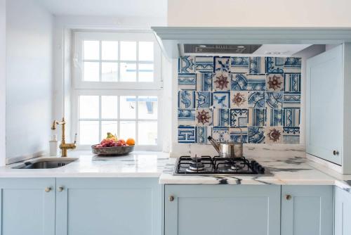 a white kitchen with a sink and a stove at Central Ericeira - Light filled with Terrace in Ericeira