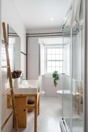 a bathroom with a sink and a glass shower at Central Ericeira - Light filled with Terrace in Ericeira
